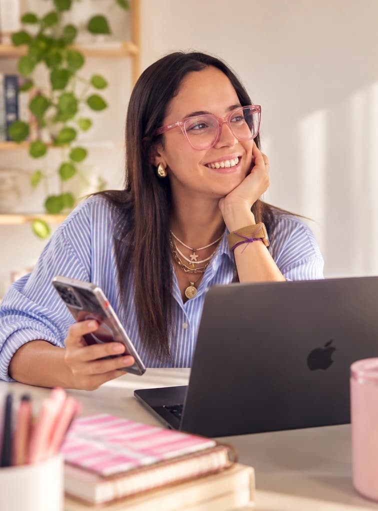 Juli trabajando en su escritorio con la computadora y el celular
