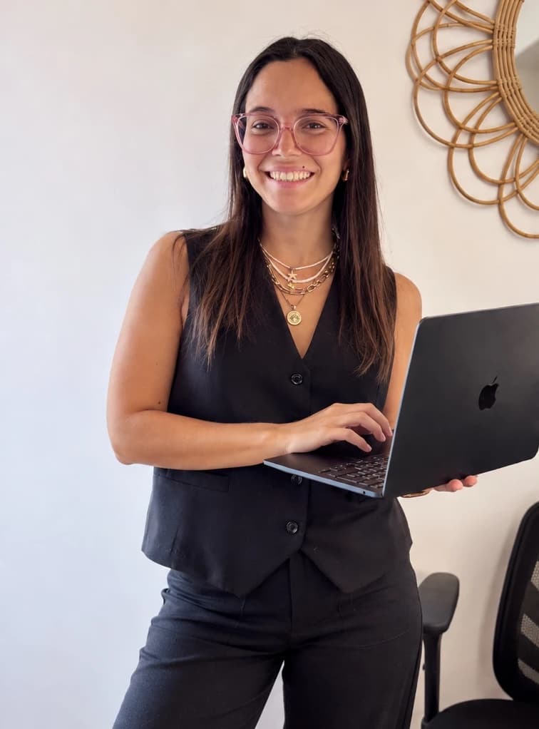 Juli, Community Manager de Redes con Juli, sonriendo con su computadora